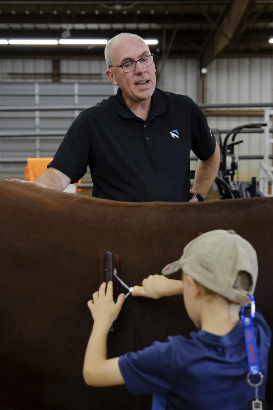 Bart Barber gives Caleb Coblentz, 5, tips on brushing heifers at a 4-H sponsored event in McKinney, Texas, on Saturday, Sept. 24, 2022. (AP Photo/Audrey Jackson)