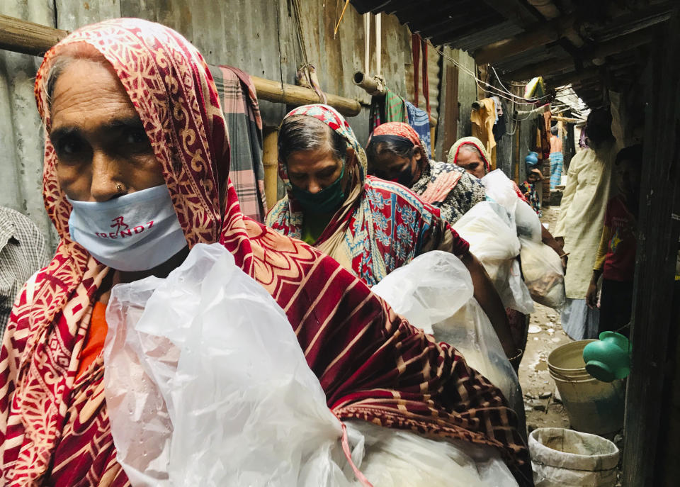 FILE - In this Thursday, Aug. 20, 2020 file photo, impoverished Bangladeshi women return home after collecting food packages distributed by Mission Save Bangladesh in Dhaka, Bangladesh. As coronavirus vaccines trickle into some of the poorest countries in Asia, Africa and the Middle East, data suggest some women are consistently missing out, in another illustration of how the doses are being unevenly distributed around the world. (AP Photo/Al-emrun Garjon, file)