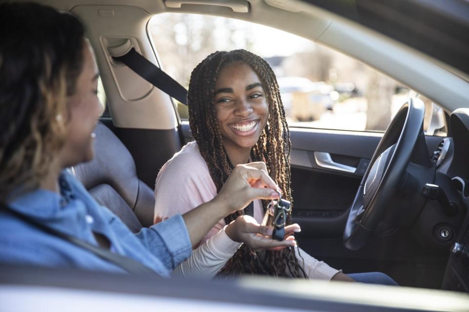 An image of a mom handing car keys to her teenage daughter.