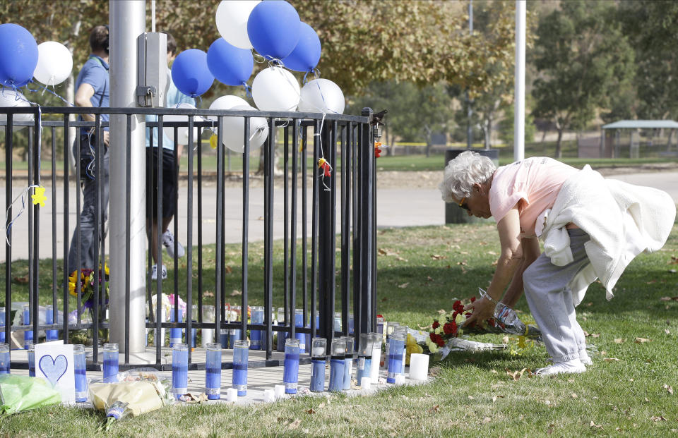 Cindy Toll places flowers at the Central Park memorial for the Saugus High School victims in Santa Clarita, Calif., Friday, Nov. 15, 2019. Investigators said Friday they have yet to find a diary, manifesto or note that would explain why a boy killed two students outside his Southern California high school on his 16th birthday. (AP Photo/Damian Dovarganes)