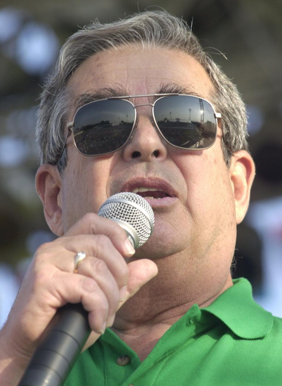 With the crowd reflected in his sunglasses, Jim Acheson talks to concert-goers on June 29, 2002, inviting them to the Southside Summerfest.