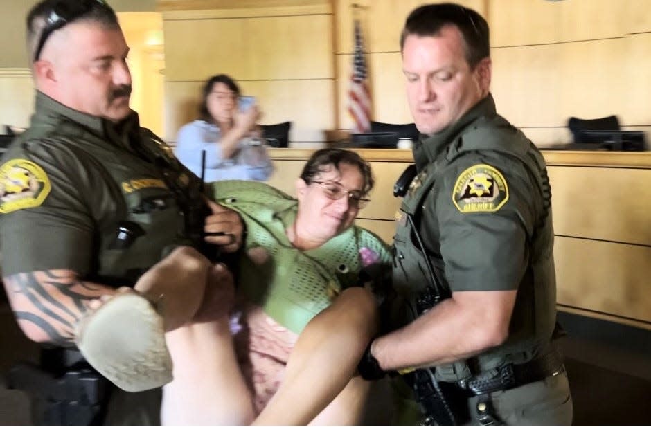 Shasta County sheriff's deputies carry Jenny Nowain of Redding from a Board of Supervisors meeting Tuesday, July 23, 2024, after she refused to leave.