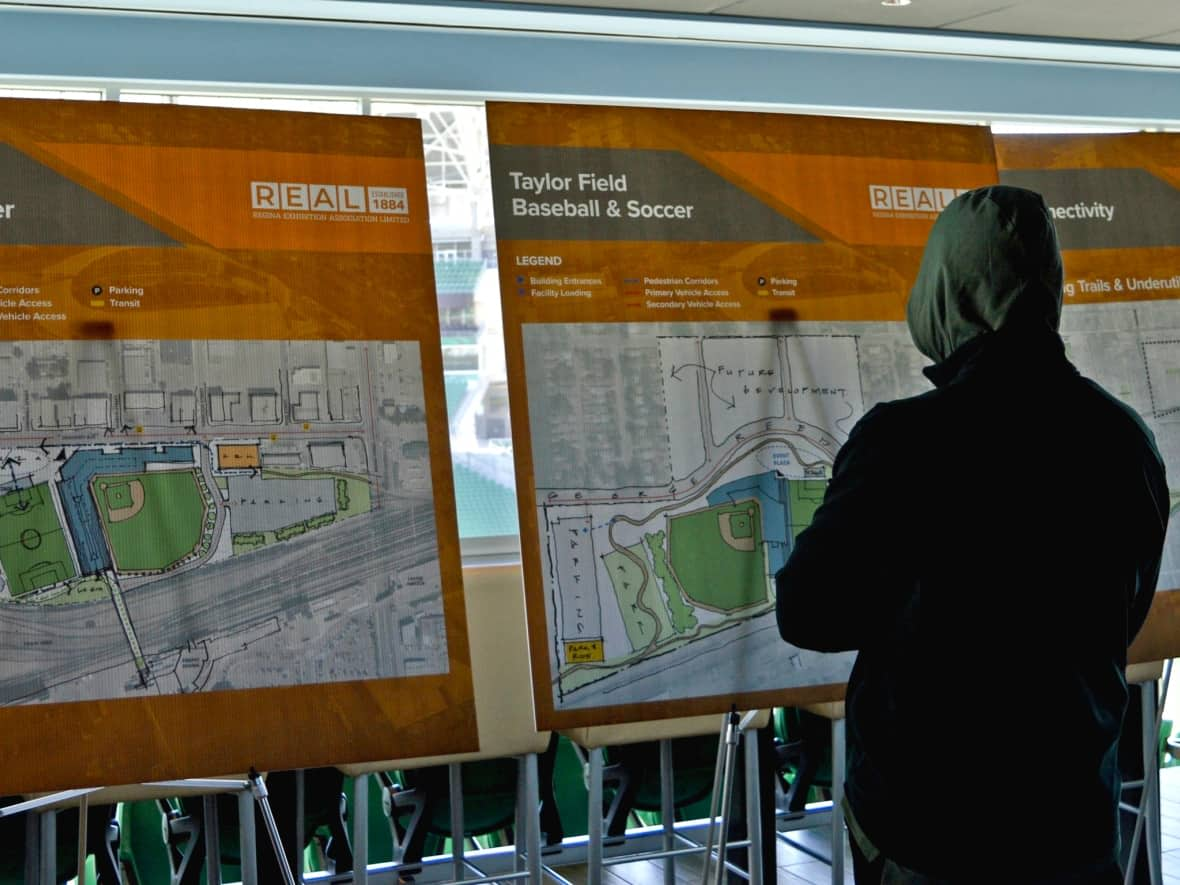 A Regina resident views two information boards about the catalyst projects that could shape the city's downtown for decades to come.  (Alexander Quon/CBC - image credit)