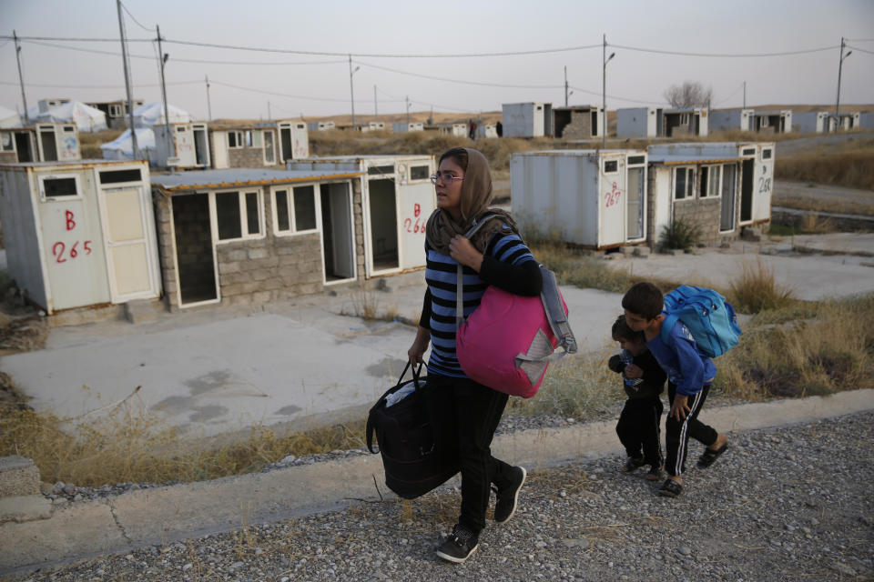 FILE - In this Oct. 17, 2019 file photo, Salwa Hanna with her children, who are newly displaced by the Turkish military operation in northeastern Syria, carry their belongings after they arrive at the Bardarash refugee camp, north of Mosul, Iraq, For months, every time Turkey threatened to invade northern Syria, Salwa Hanna told her husband they should take their children and flee from the border town of Kobani. And every time, he told her not to worry, because the Americans were there. Now the Christian family is among an estimated 160,000 Syrians who have fled Turkey’s offensive, which began last week after President Donald Trump announced he would move U.S. forces out of the way, abandoning their Kurdish allies. (AP Photo/Hussein Malla)