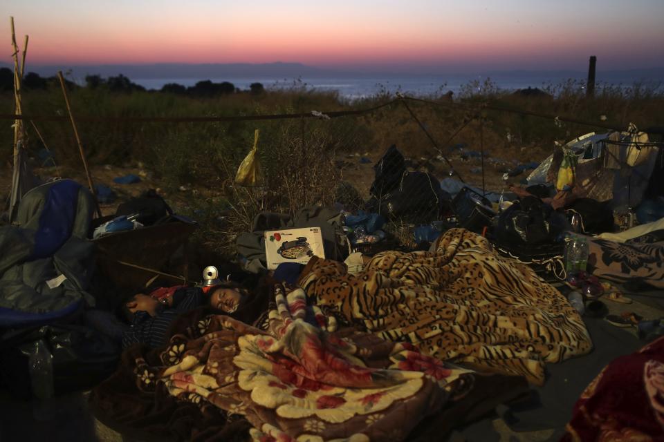 Migrants sleep as they remained camped out on a road leading from Moria to the capital of Mytilene, on the northeastern island of Lesbos, Greece, Thursday, Sept. 17, 2020. Fires swept through the overcrowded camp at Moria on two nights last week, prompting more than 12,000 migrants and refugees to flee. Most of them remain without shelter even though emergency tents are available at another island site where a new camp is being built. (AP Photo/Petros Giannakouris)