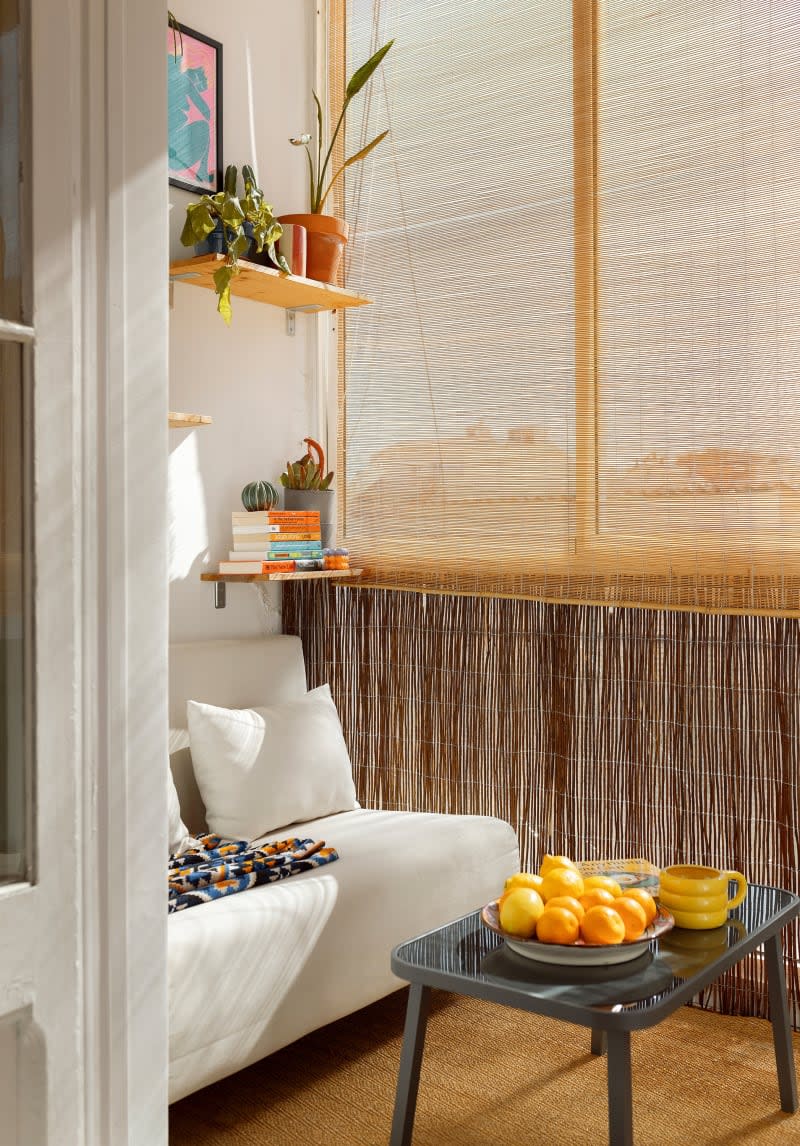 A sunroom with wooden shelves, large windows, and a white couch.