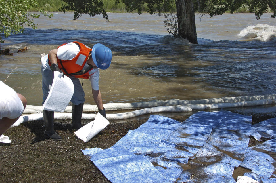 FILE - In this July 4, 2011, file photo, an Exxon Mobil contractors mops up oil along the Yellowstone River near Laurel, Mont. U.S. transportation officials have finalized long-delayed measures meant to prevent pipeline spills and deadly gas explosions but don't address recommended steps to lessen accidents once they occur. (AP Photo/Matthew Brown, File)