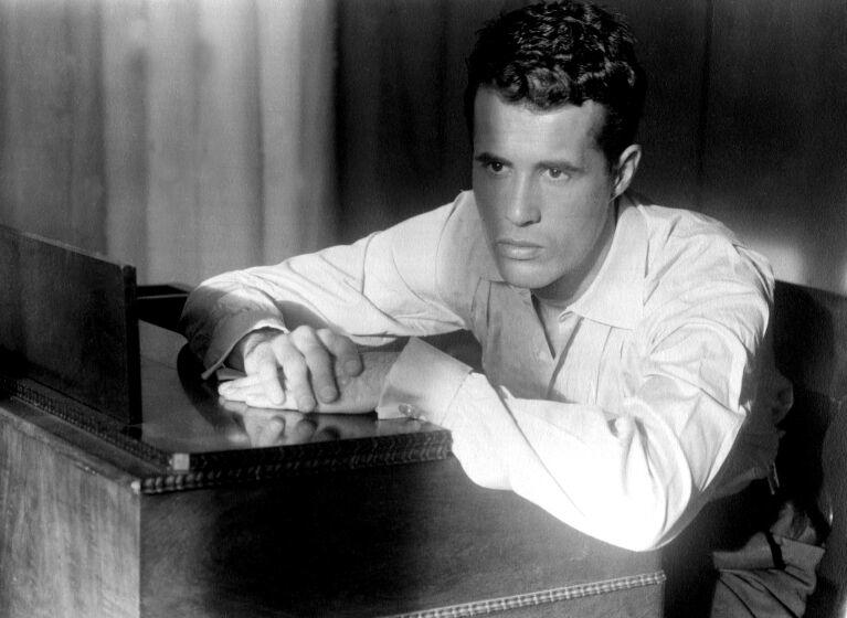 Portrait of American film director Kenneth Anger seated at a piano, Los Angeles, California, 1955.