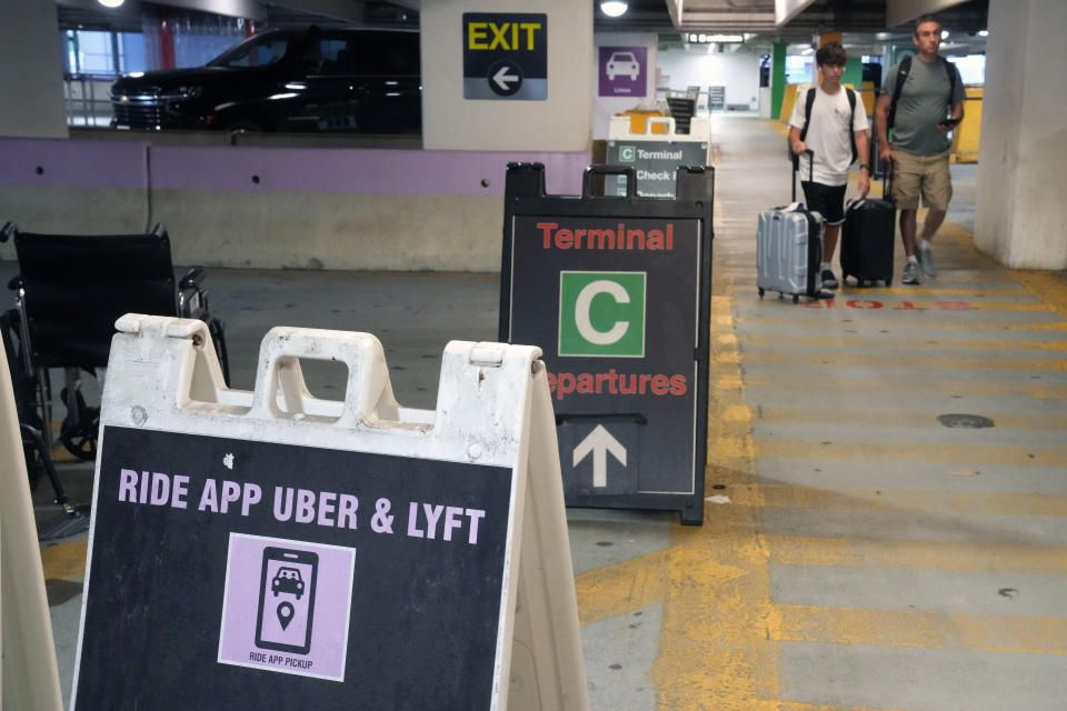 Travelers enter a pick up location for ride-hailing companies, including Uber and Lyft, Tuesday, July 9, 2024, in the lower level of a parking garage at Logan International Airport, in Boston. Drivers for ride-hailing companies in Massachusetts are pushing ahead with what they describe as a first-of-its-kind ballot question that would win union rights if approved. (AP Photo/Steven Senne)