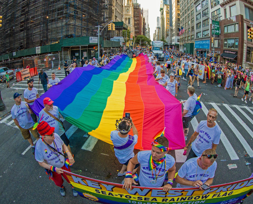 In this photo provided by the Florida Keys News Bureau, representatives from Key West, Fla., carry a 100-foot-long rainbow flag Sunday, June 30, 2019, during the LGBTQ Pride march in New York. The flag is a section of a 1.25-mile long rainbow flag unfurled in Key West in 2003 to mark the 25th anniversary of the creation of the iconic LGBTQ banner conceived by the late Gilbert Baker. Sunday's march highlighted events marking five decades of pride following the 1969 Stonewall Inn police raid that sparked the modern-day gay rights movement. (Jonathan Atkin/Florida Keys News Bureau via AP)