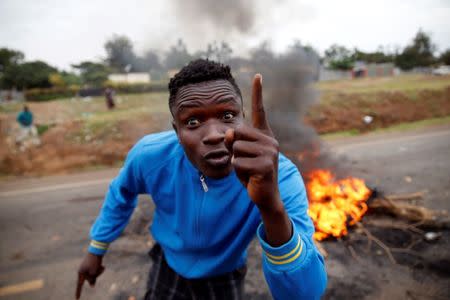 A protester, supporting opposition leader Raila Odinga, stands near burning tires during clashes in Kisumu, Kenya August 12, 2017. REUTERS/Baz Ratner