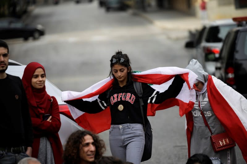 A protester holds a Lebanese flag at a roadblock during ongoing anti-government demonstrations in Beirut