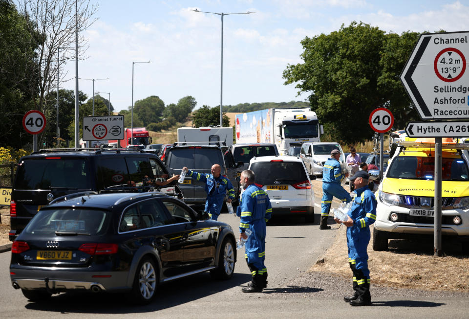 Members of the Coast Guard hand out bottled water to vehicles queuing to enter the Eurotunnel terminal in Folkestone, Britain, July 24, 2022. REUTERS/Henry Nicholls