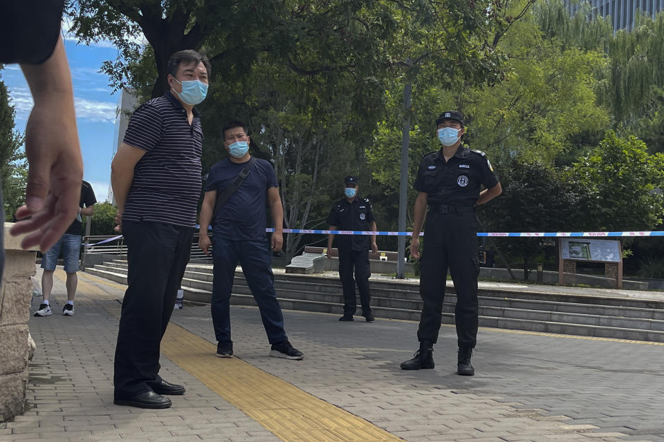 Plainclothes policemen and security guards wearing face masks stand guard as they stop journalists preventing them from getting near the No. 1 Intermediate People's Court, where Zhou Xiaoxuan, a former intern at state broadcaster China Central Television, was filling her appeal case against CCTV host Zhu Jun for groping and forcibly kissing her in 2014, in Beijing, Wednesday, Aug. 10, 2022. A Chinese court rejected an appeal Wednesday from a woman seeking an apology and damages in a high-profile case from the country's short-lived #MeToo movement. (AP Photo/Andy Wong)