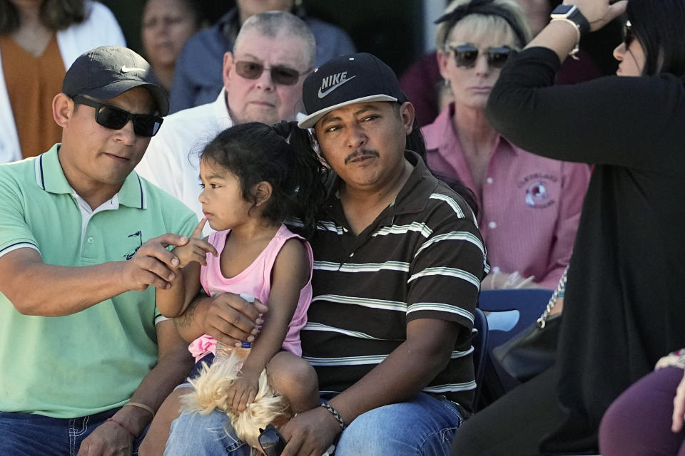 Mass shooting survivor Wilson Garcia, center, holds a young girl during a vigil for his son Daniel Enrique Laso, 9, Sunday, April 30, 2023, in Cleveland, Texas. Garcia's son and wife were killed in the shooting Friday night. The search for a Texas man who allegedly shot his neighbors after they asked him to stop firing off rounds in his yard stretched into a second day Sunday, with authorities saying the man could be anywhere by now. The suspect fled after the shooting Friday night that left five people dead. (AP Photo/David J. Phillip)