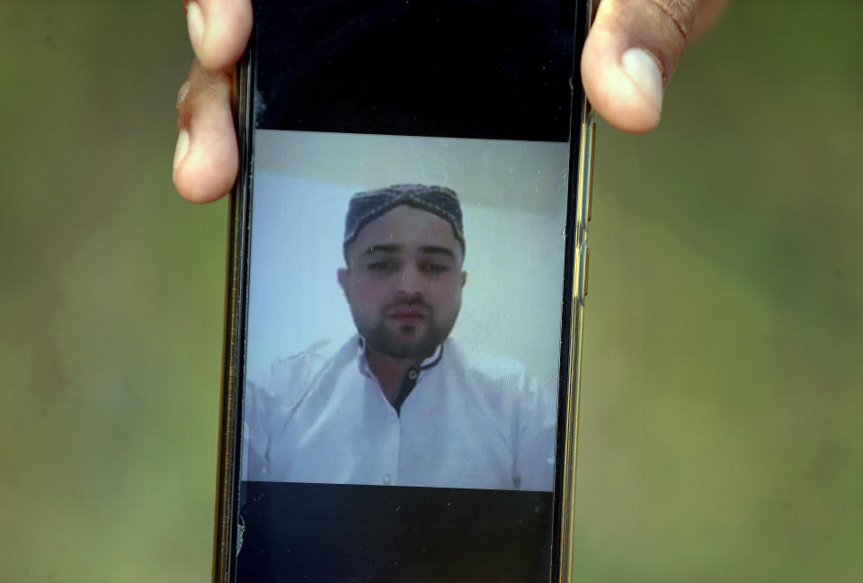 A villager displays a picture of Ali Hassan, a suspect in an attack on two people with a meat cleaver in Paris last month, in his native village of Kotli Qazi, Pakistan, Saturday, Oct. 3, 2020. Hassan is in jail in Paris, but just three years ago he started out like other young men who leave Pakistan for Europe with dreams of a better life. (AP Photo/Anjum Naveed)