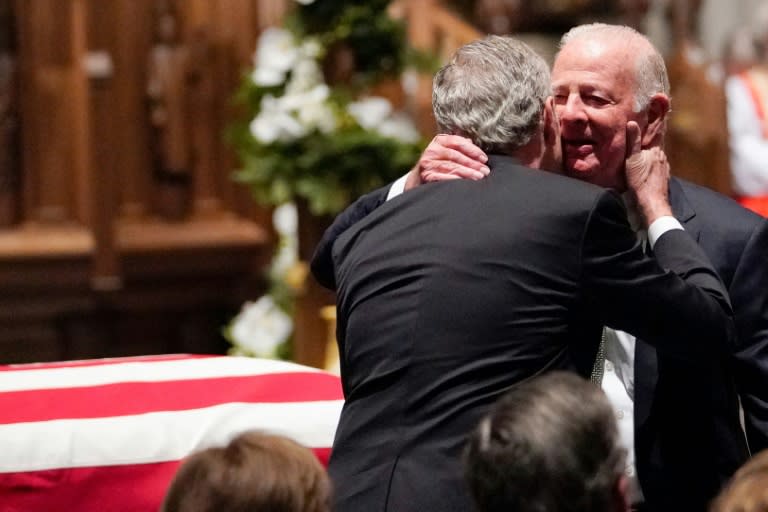 Former US President George W. Bush embraces former US secretary of State James Baker (R) after he gave a eulogy during the funeral for former president George H.W. Bush in Houston