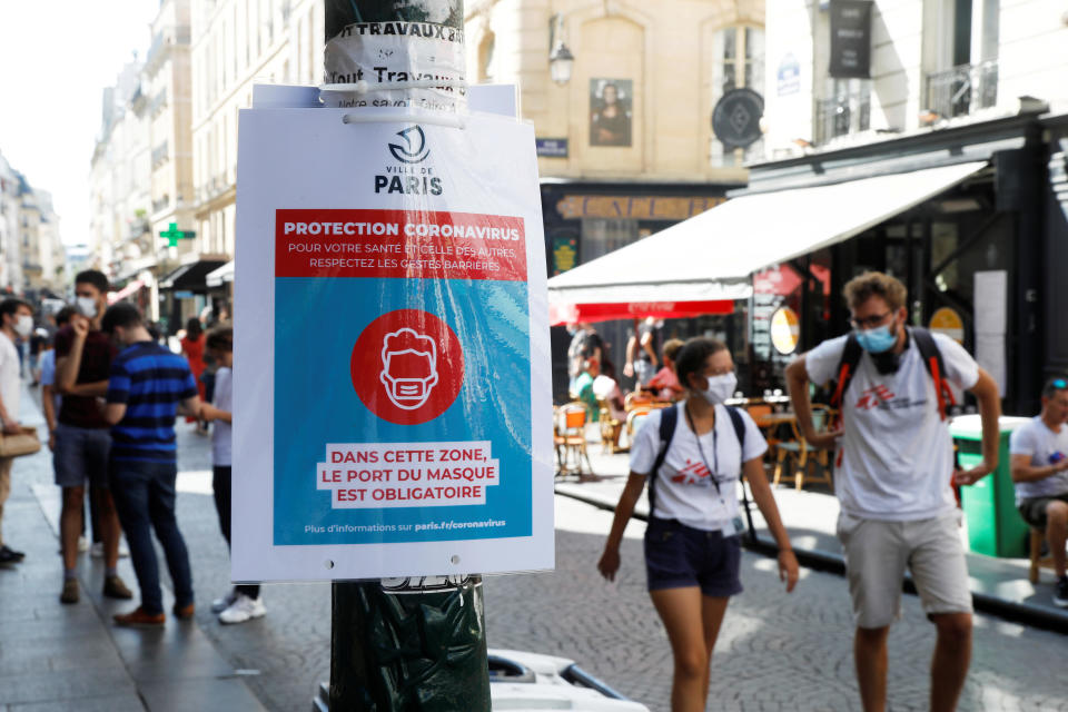 Pedestrians wearing protective face masks walk by a coronavirus disease (COVID-19) information sign, as France reinforces mask-wearing as part of efforts to curb a resurgence of the coronavirus disease (COVID-19) across the country, France, August 13, 2020. / Credit: CHARLES PLATIAU/REUTERS