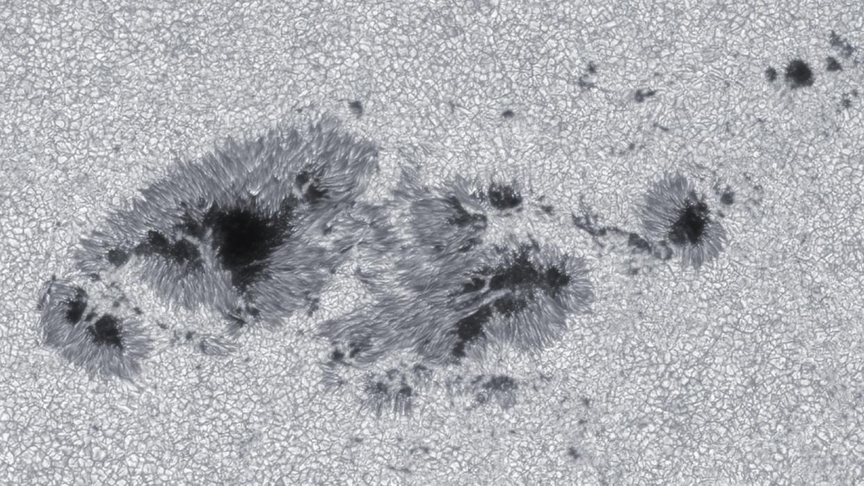  A black and white image of a large dark sunspot on the surface of the sun 