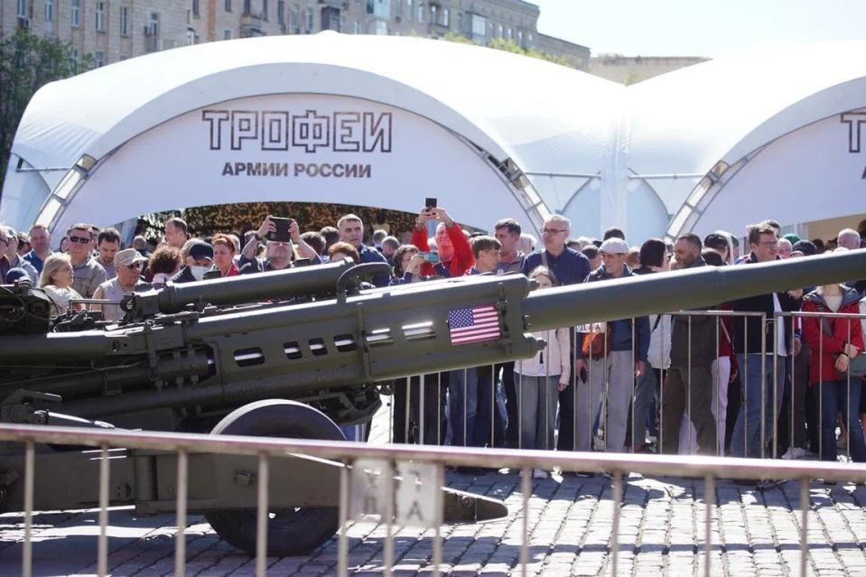 Visitors take photos of an American M777 Howitzer.