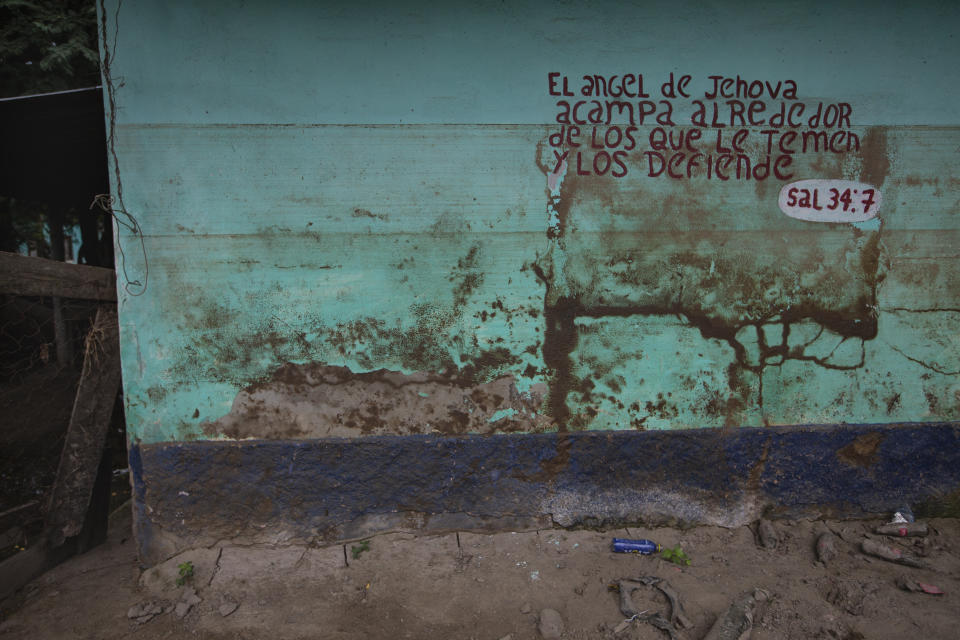 Stains left by mud and water from last year's hurricanes Eta and Iota mark a wall decorated by a Bible passage in the Saviñon Cruz neighborhood of San Pedro Sula, Honduras, Tuesday, Jan. 12, 2021. The words say in Spanish "The angel of the Lord encamps around those who fear him, and he delivers them. Psalm 34:7" (AP Photo/Moises Castillo)