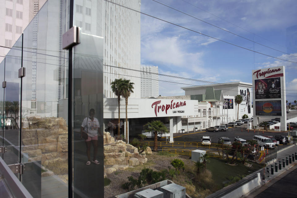 FILE - A person, reflected in glass, walks near the Tropicana Las Vegas, May 16, 2023, in Las Vegas. The Tropicana Las Vegas, a Sin City namesake for more than six decades, is slated to shut its doors in April 2024 to make room for a $1.5 billion Major League Baseball stadium, Bally's Corp. announced Monday, Jan. 29, 2024. (AP Photo/John Locher, File)