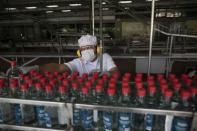 A worker inspects bottles of antiseptic alcohol at the Santa Teresa rum factory in La Victoria, Aragua state, Venezuela, Wednesday, April 1, 2020. Venezuela's premier rum distillery and one of Venezuela's few private businesses says that most of its production will be for antiseptic alcohol, in an effort to help contain the spread of the new coronavirus. (AP Photo/Ariana Cubillos)