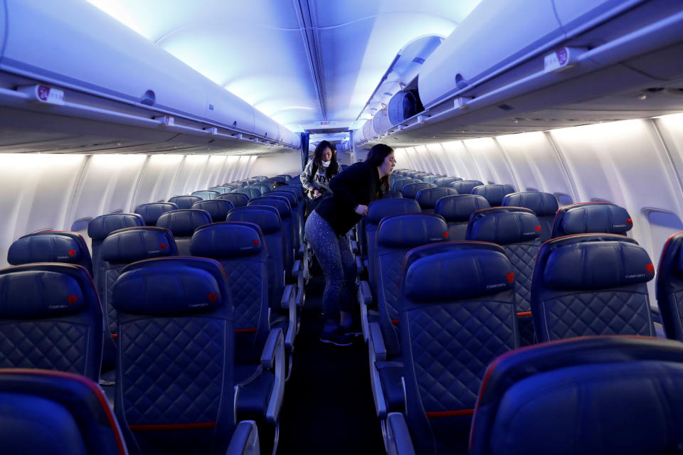 Air travelers grab carry-on luggage behind rows of empty seats aboard a Delta flight, as coronavirus disease (COVID-19) disruption continues across the global industry, from New York's JFK International Airport to San Francisco, California, U.S., March 17, 2020. REUTERS/Shannon Stapleton     TPX IMAGES OF THE DAY