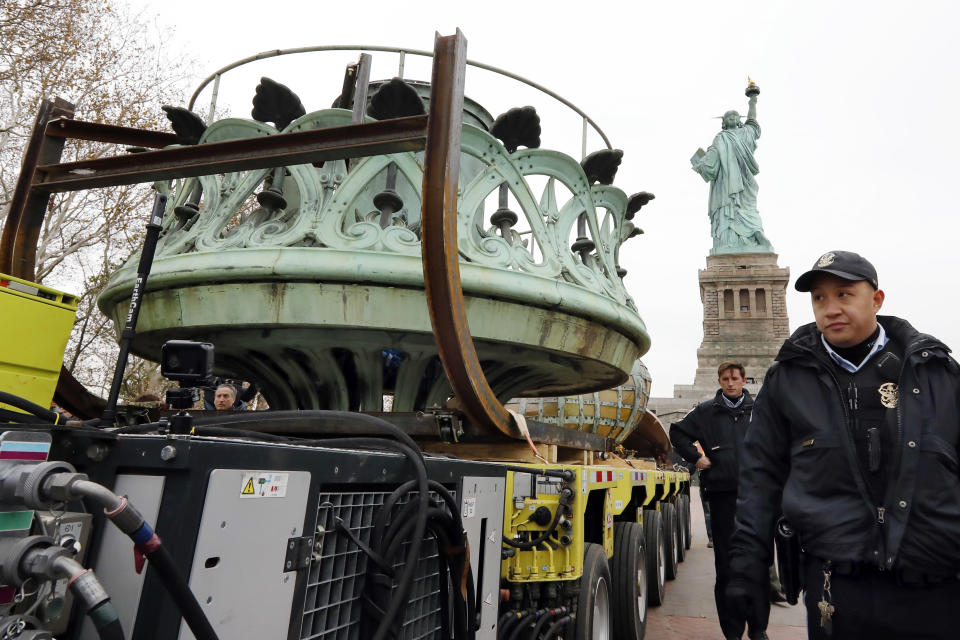 The original torch of the Statue of Liberty rides on a hydraulically stabilized transporter, Thursday, Nov. 15, 2018, in New York. The torch, which was removed in 1984 and replaced by a replica, was being moved into what will become its permanent home at a new museum on Liberty Island, background. (AP Photo/Richard Drew)