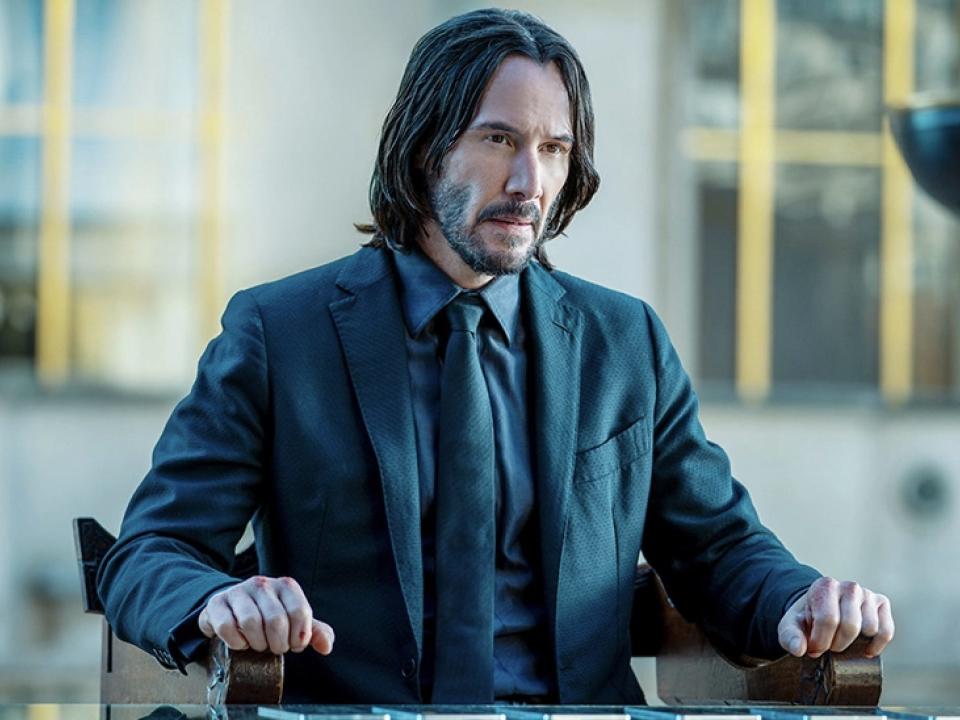 Keanu Reeves as John Wick sat at a table in Paris.