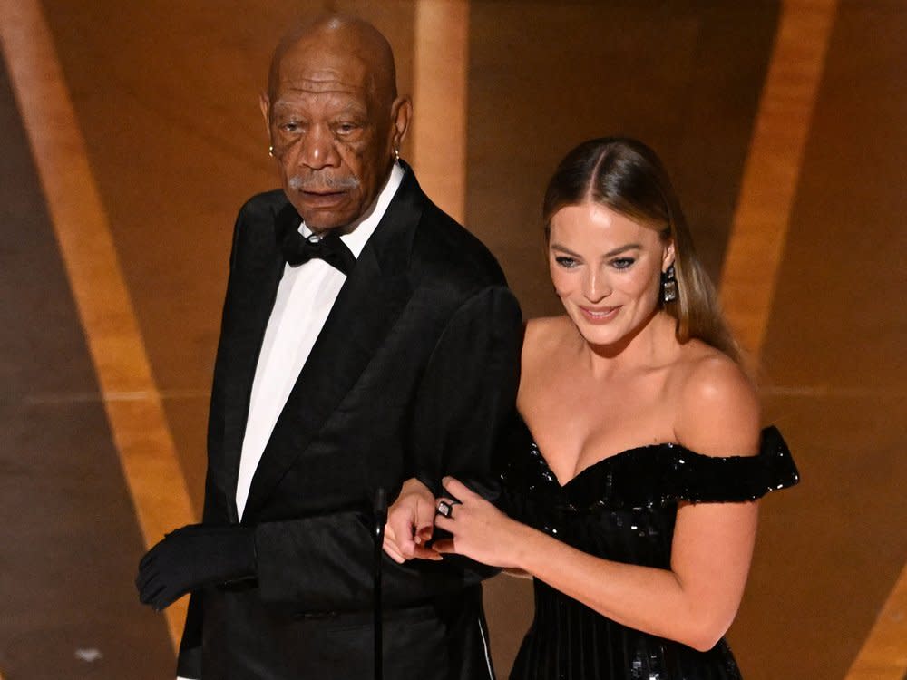 Morgan Freeman mit Margot Robbie und dem Handschuh auf der Oscarbühne. (Bild: PATRICK T. FALLON/AFP via Getty Images)