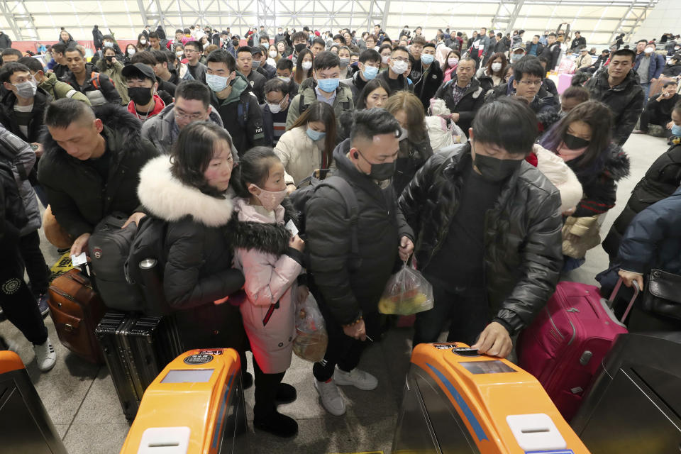 Viajeros equipados con máscaras hacen fila ante los tornos para acceder a una estación de tren en Nantong, en la provincia oriental de Jiangsu, en China, el 22 de enero de 2020. (Chinatopix vía AP)