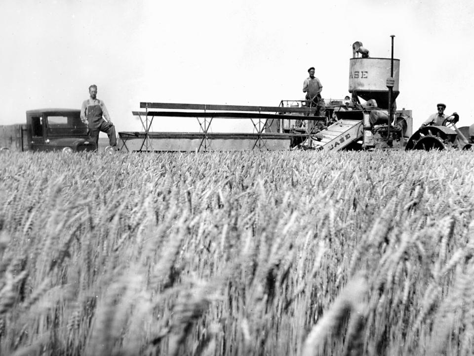 A group of farmers with their farm equipment in a wheat field, circa 1925.