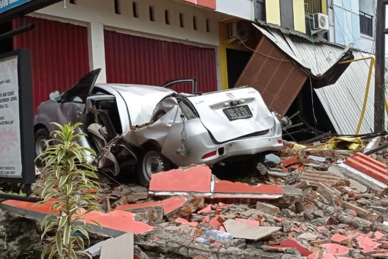 A damaged car and buildings are seen following an earthquake in Mamuju