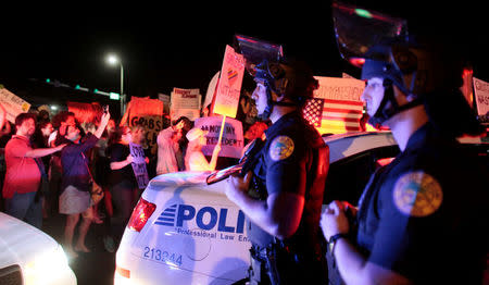 Police officer stand guard while people protest against U.S. President-elect Donald Trump in Miami, Florida, U.S. November 11, 2016. REUTERS/Javier Galeano