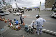 Workers set up a barricade near the Lawson convenience store, a popular photo spot framing a picturesque view of Mt. Fuji in the background Tuesday, April 30, 2024, at Fujikawaguchiko town, Yamanashi Prefecture, central Japan. The town of Fujikawaguchiko, known for a number of popular photo spots for Japan's trademark of Mt. Fuji, on Tuesday began to set up a huge black screen on a stretch of sidewalk to block view of the mountain in a neighborhood hit by a latest case of overtourism in Japan. (AP Photo/Eugene Hoshiko)
