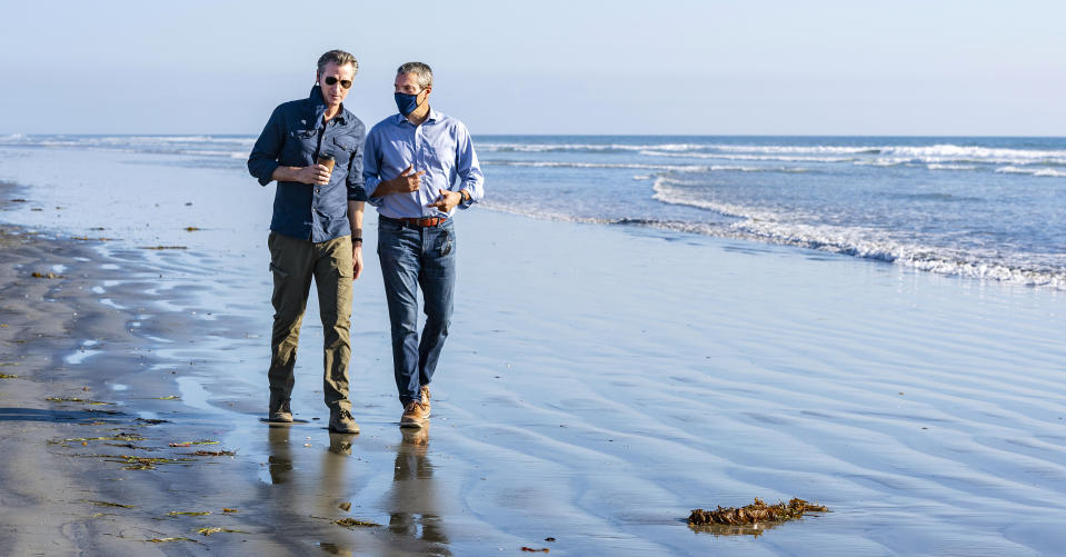 California Gov. Gavin Newsom, left, walks with Wade Crowfoot, California's Natural Resources Secretary, along Bolsa Chica State Beach in Huntington Beach, Calif., site of the recent offshore oil spill, on Tuesday, Oct. 5, 2021. Newsom proclaimed a state of emergency in Orange County to support the emergency response to the oil spill that originated in federal waters. (Mark Rightmire/The Orange County Register via AP)