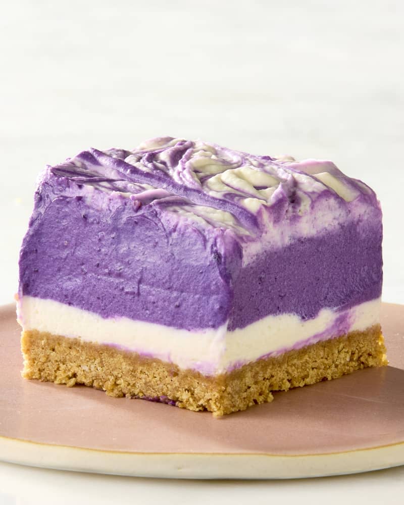 A single ube dessert bar piece on a plate with layers of purple, white, and cracker crust showing.