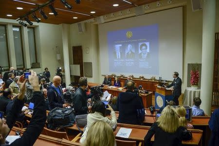 Members of the media take photos of the screen as professor Urban Lendahl (R) announces the 2015 Nobel laureates in medicine during a news conference at the Karolinska Institute in Stockholm October 5, 2015. REUTERS/Fredrik Sandberg/TT News Agency