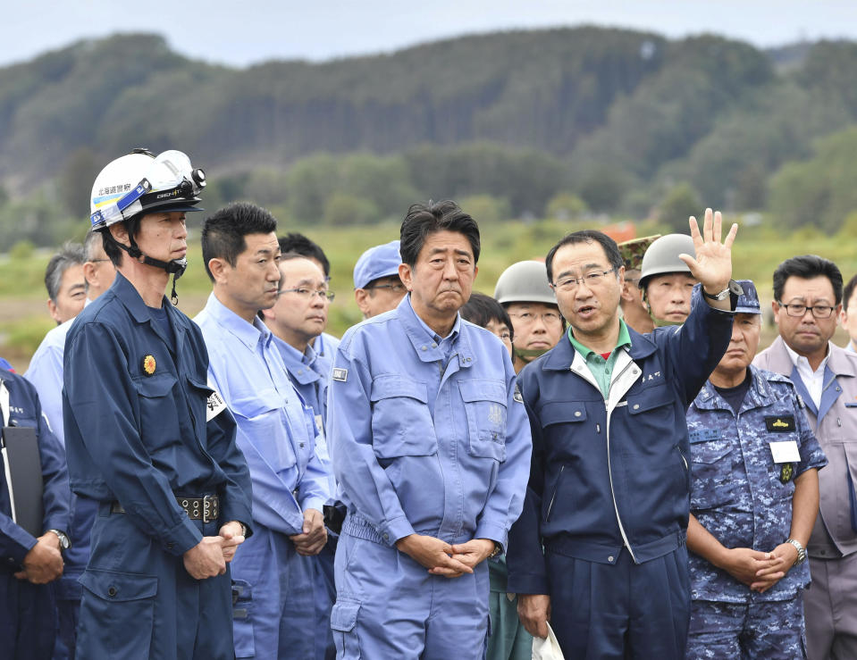 Japan's Prime Minister Shinzo Abe, center, visits the site of a landslide triggered by the Sept. 6, earthquake in Atsuma, Hokkaido, northern Japan Sunday, Sept. 9, 2018. Japanese authorities say dozens of people have been confirmed dead from a powerful earthquake that struck the northern island of Hokkaido last week. (Kyodo News via AP)