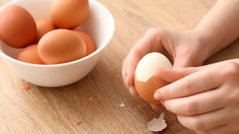 person peeling hard boiled egg