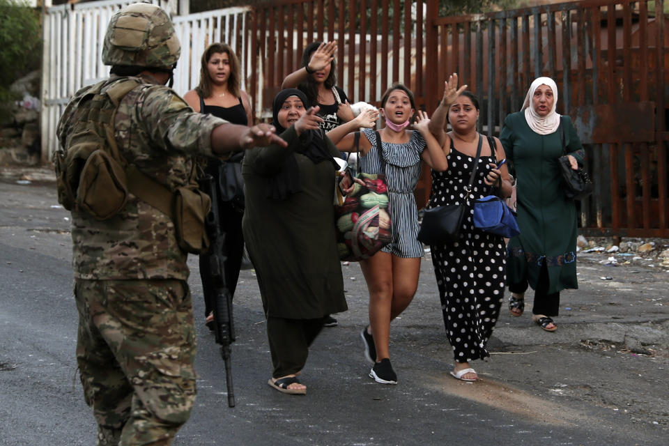 People carry their belongings as they flee their houses after heavy clashes in the coastal town of Khaldeh, south of Beirut, Lebanon, Sunday, Aug. 1, 2021. At least two people were killed on Sunday south of the Lebanese capital when gunmen opened fire at the funeral of a Hezbollah commander who was killed a day earlier, an official from the group said. (AP Photo/Bilal Hussein)