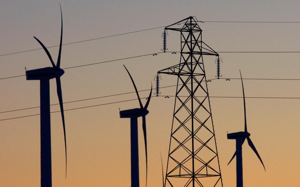 Electricity pylons and wind turbines are silhouetted at the Scottish Power-owned Dun Law West wind farm near Edinburgh, 2010