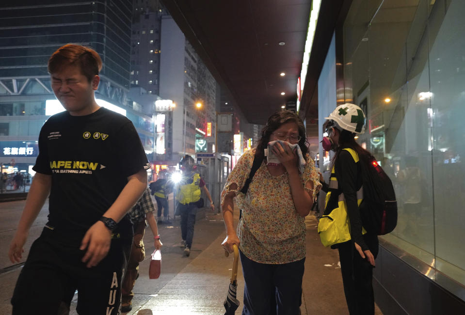 Residents react to tear gas on the streets in Hong Kong on Sunday, Oct. 27, 2019. Hong Kong police fired tear gas Sunday to disperse a rally called over concerns about police conduct in monthslong pro-democracy demonstrations, with protesters cursing the officers and calling them "gangster cops." (AP Photo/Vincent Yu)