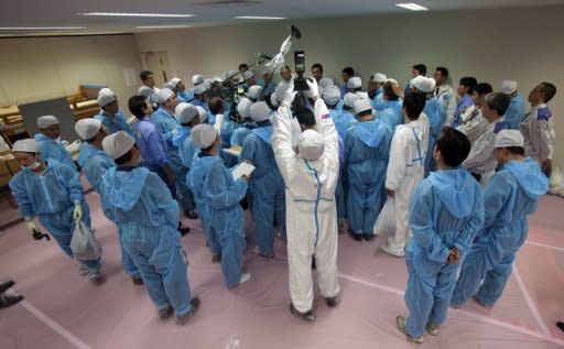 This file photo shows members of the media, wearing protective suits, interviewing Japan's Minister of the Environment Goshi Hosono and then Chief of the Dai-ichi nuclear plant Masao Yoshida, inside the emergency operation center at the crippled plant, in 2011