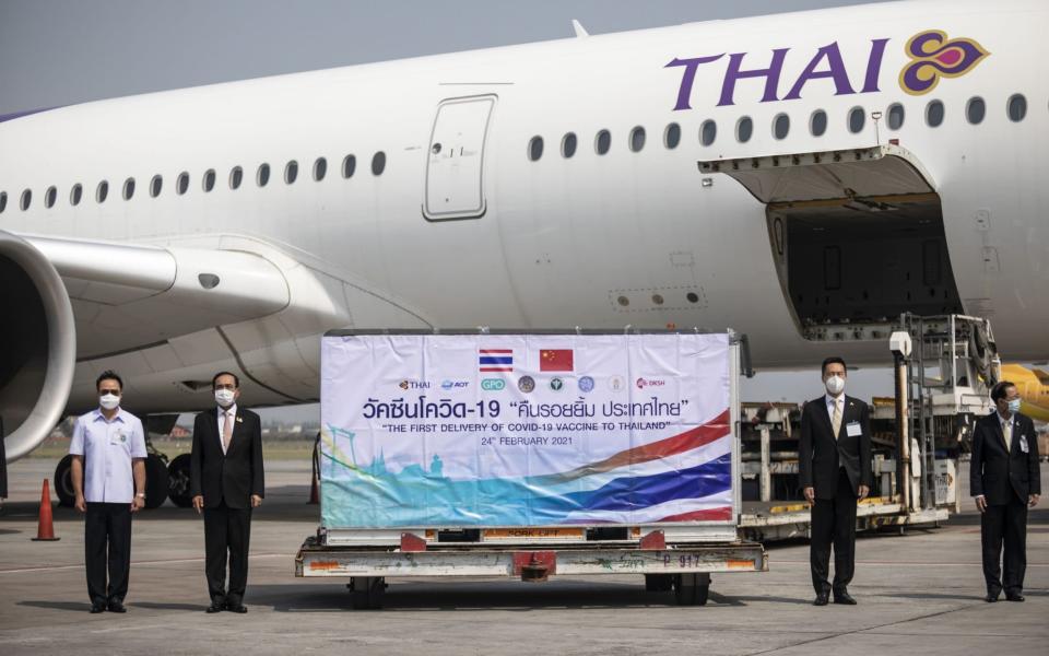 Prayuth Chan-Ocha, Thailand's prime minister, second left, next to an Envirotainer AB refrigerated shipping container with the first shipment of Sinovac Biotech Ltd. coronavirus vaccine as it is unloaded from a Thai Airways cargo flight at Suvarnabhumi Airport in Bangkok, - Andre Malerba/Bloomberg