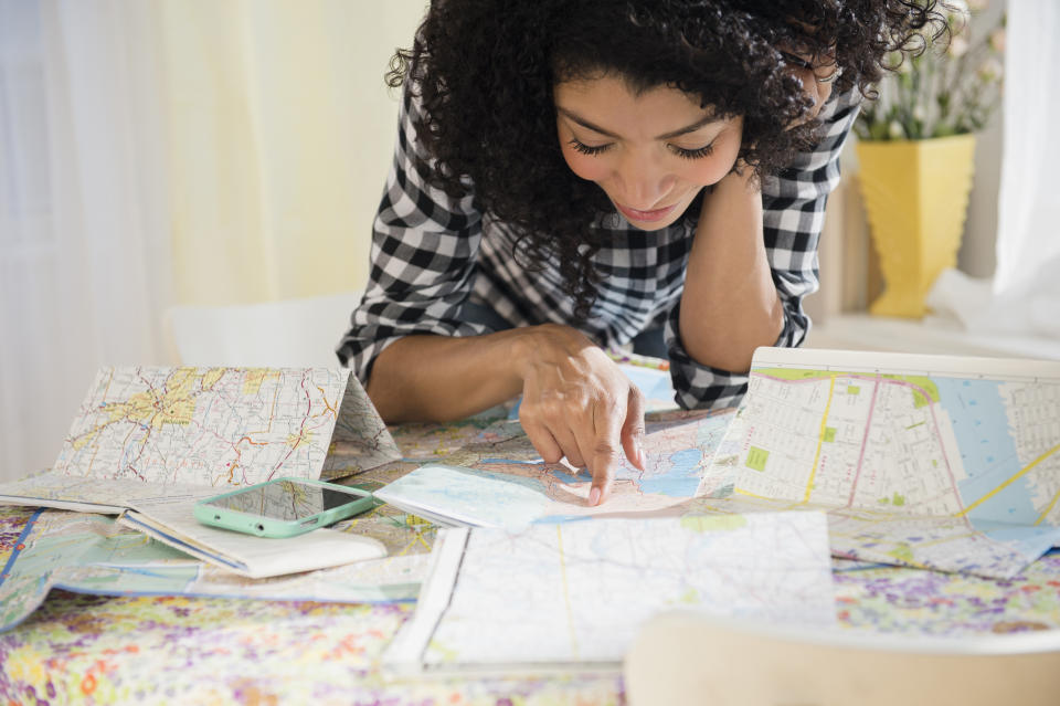 woman planning road trip with maps