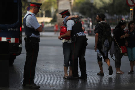 Pilar Revilla, 75, hugs a Catalan Mossos d'Esquadra officer after visiting an impromptu memorial where a van crashed into pedestrians at Las Ramblas in Barcelona, Spain, August 20, 2017. REUTERS/Susana Vera
