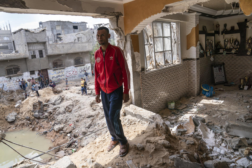 Nader al-Masri, a long-distance runner who participated in dozens of international competitions, including the 2008 Olympics, stands inside his severely damaged home beside the crater where the home of Ramez al-Masri was destroyed by an air-strike prior to a cease-fire reached after an 11-day war between Gaza's Hamas rulers and Israel, Sunday, May 23, 2021, in Beit Hanoun, the northern Gaza Strip. (AP Photo/John Minchillo)