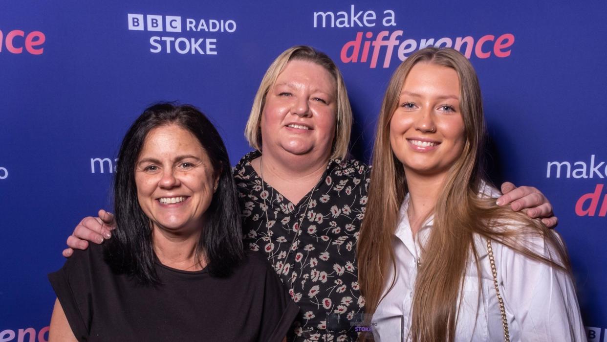 Three women smile as they pose for the camera